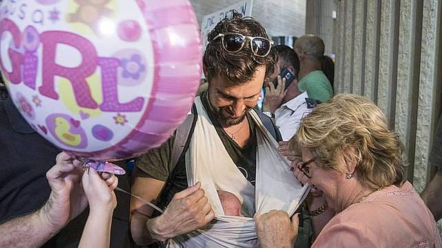 Un gai israel muestra uno de los bebs nacidos en Nepal de madre de alquiler, a su llegada al aeropuerto de Tel Aviv